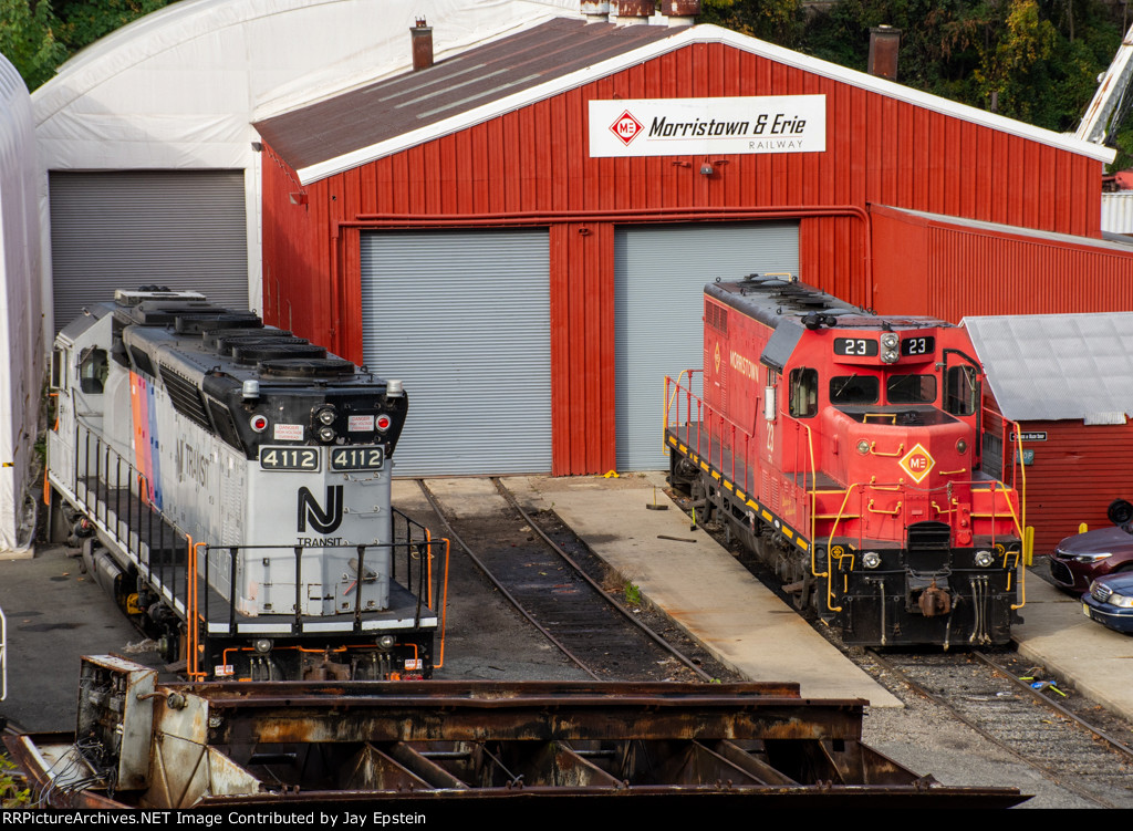 NJT 4112 and M&E 23 sit outside the shops 